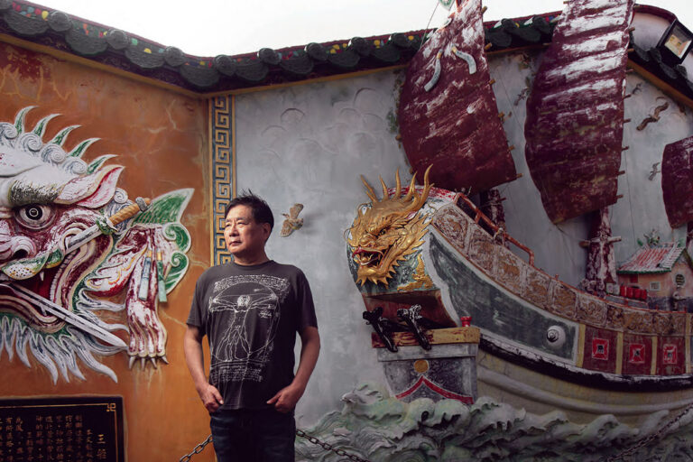 安平古堡旁的巷弄中建於一八一七年的文龍殿內，楊憲宏獨自站在王船與劍獅的壁飾前。(攝影／劉子正)
