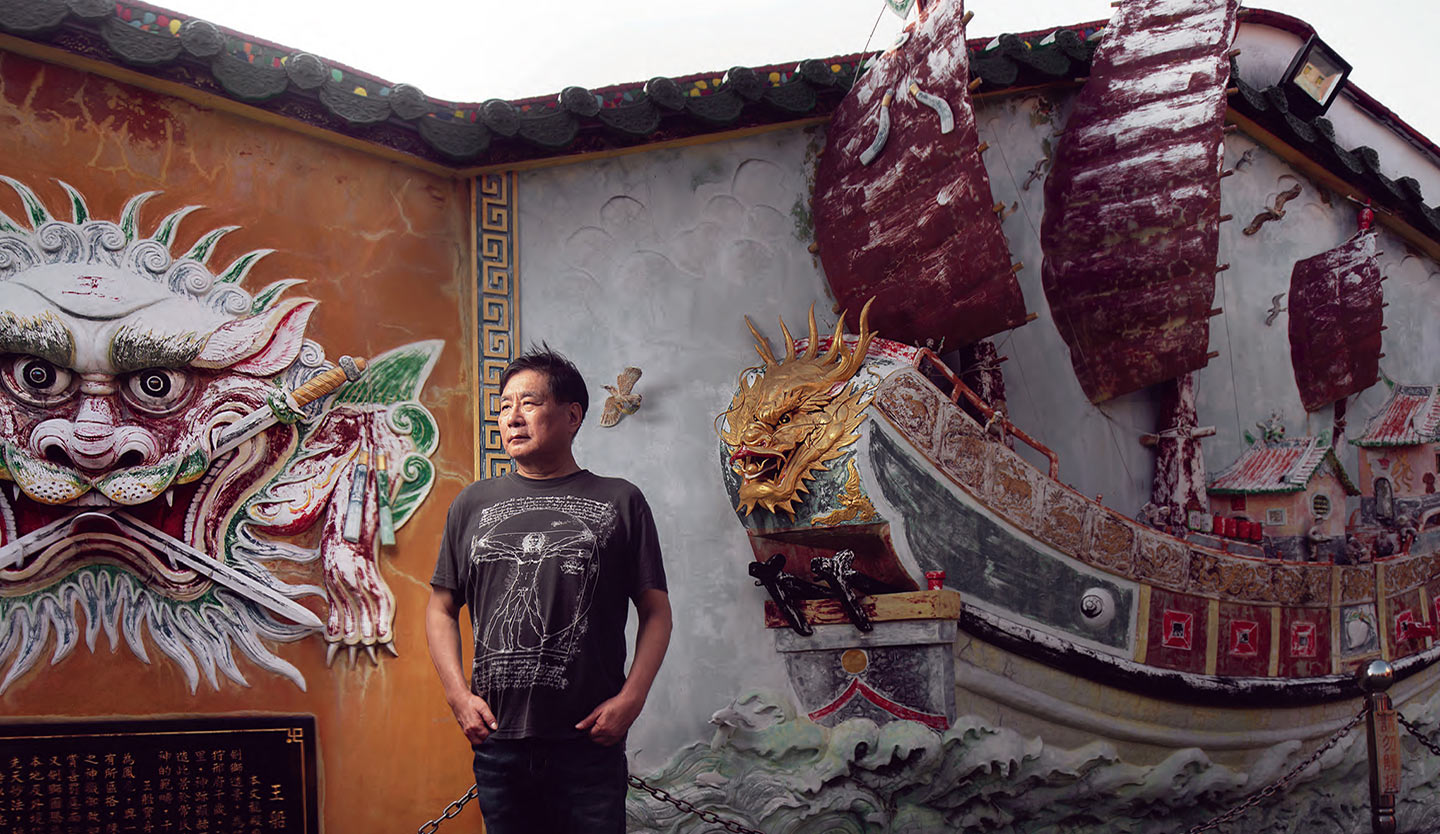 安平古堡旁的巷弄中建於一八一七年的文龍殿內，楊憲宏獨自站在王船與劍獅的壁飾前。(攝影／劉子正)