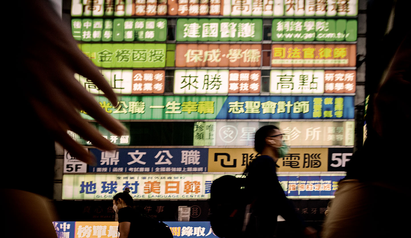 人來人往的台北車站街頭，大樓牆上掛滿醒目招牌。(攝影／安培淂)