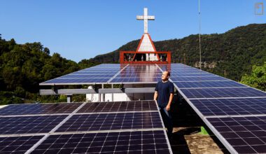 比亞外教會牧師達亞哈內爬上教堂屋頂，開心分享一片片光電板。(攝影／安培淂)