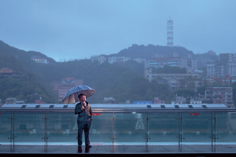 冬季煙雨朦朧，曹銘宗留影於基隆港東岸旅客中心的觀海平台上。(攝影／劉子正)